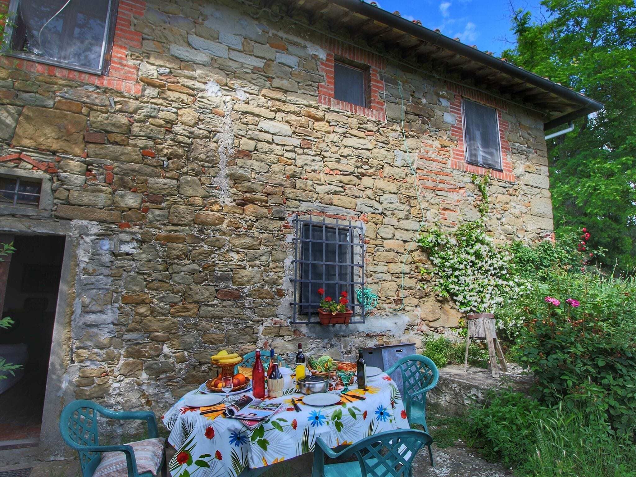 Un edificio de piedra con una mesa dispuesta para una comida, rodeado de follaje.