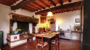 Una cocina rústica con chimenea de piedra, vigas de madera y una mesa de comedor para cuatro.