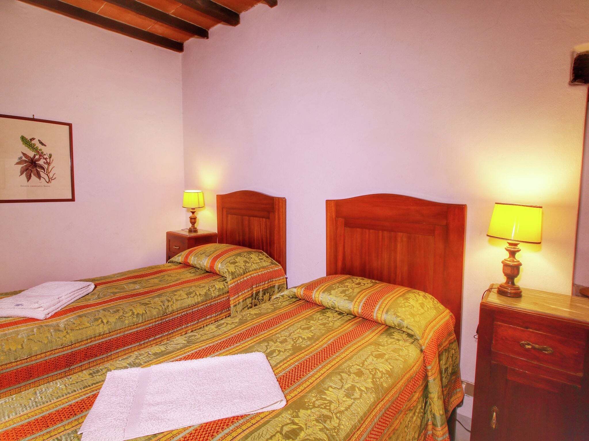 A double room with two beds, each with a wooden headboard, a nightstand with a lamp, and a framed botanical print on the wall.