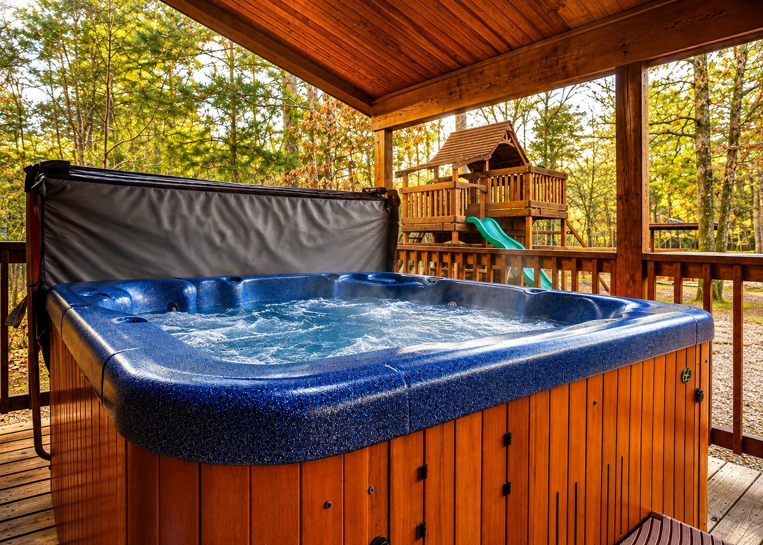 A hot tub on a wooden deck with a wooden playhouse in the background.