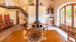 Amplia sala de estar con una mesa de comedor de madera, sillas tapizadas en rojo, una escalera y una cocina con armarios de madera y un ventanal grande.