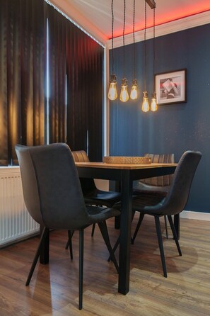 Un comedor con mesa de madera, sillas negras e iluminación colgante.