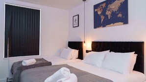 Habitación de hotel con dos camas, un mapa del mundo en la pared y una ventana con cortinas.