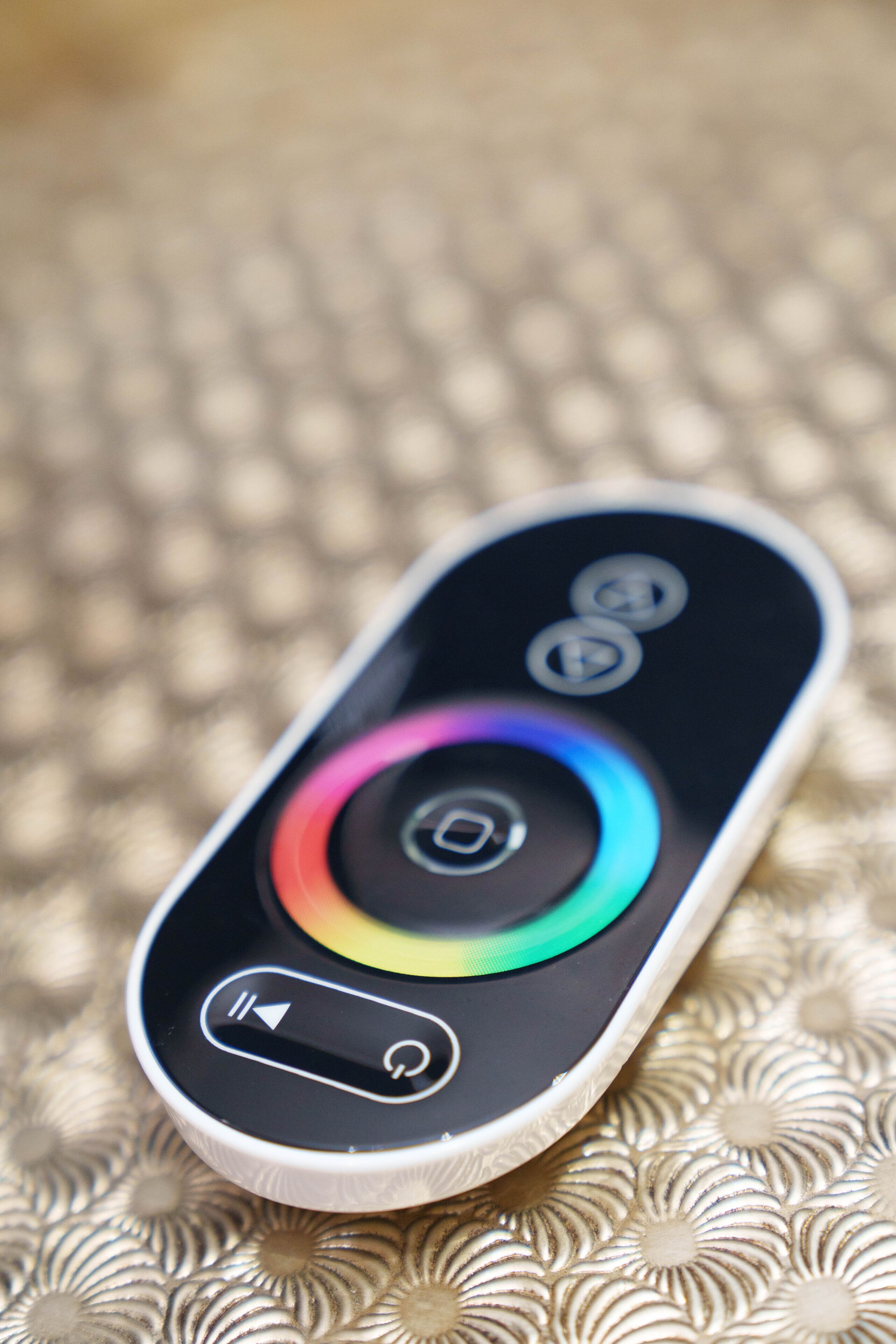 A remote control with a circular color wheel and directional buttons.