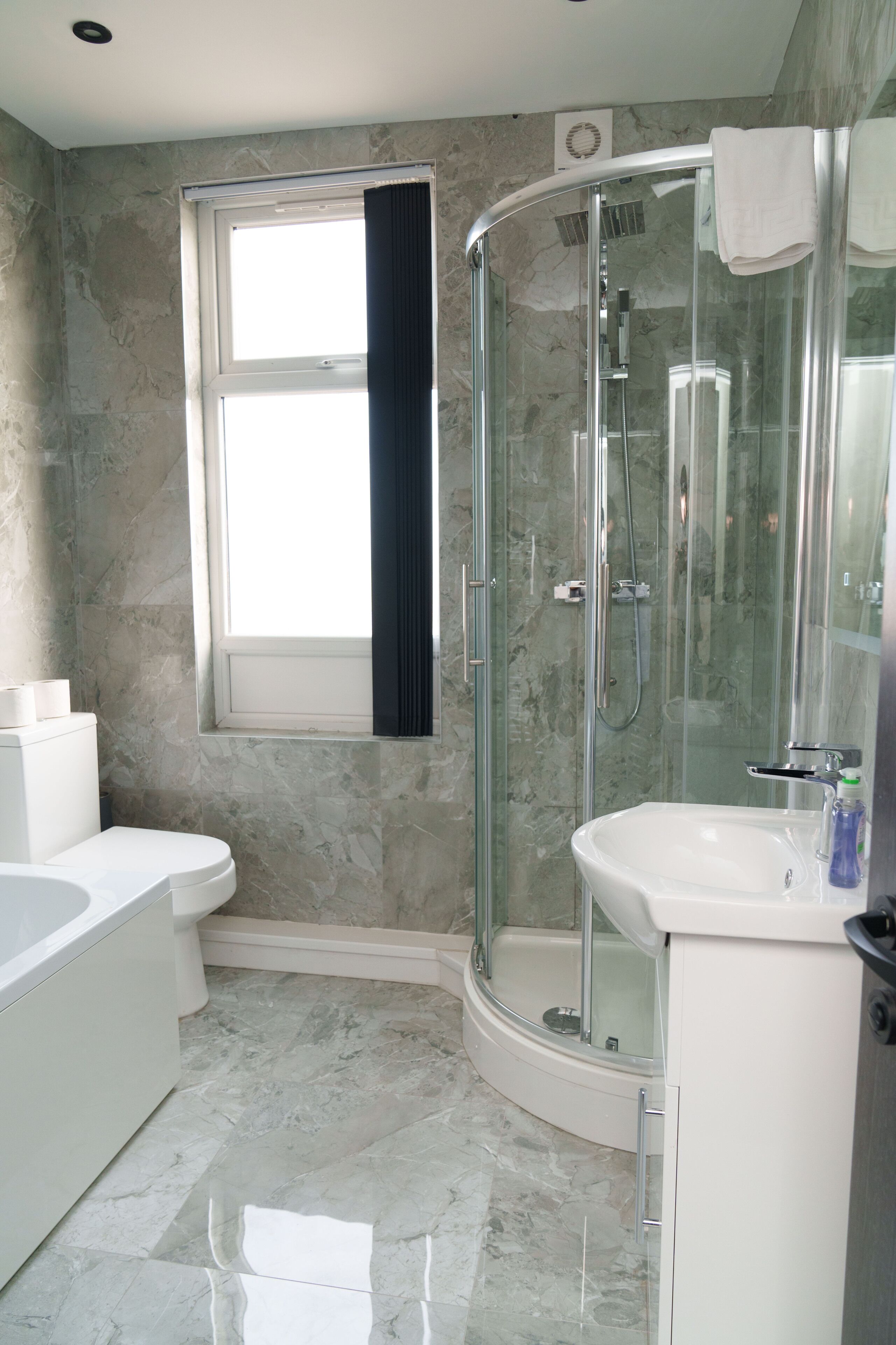 A bathroom with a glass-enclosed shower, a white sink, and a toilet.