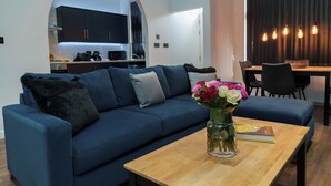 Una sala de estar moderna con un sofá azul, una mesa de centro de madera y un jarrón de flores.