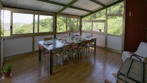 Un comedor con una mesa dispuesta para seis personas, sillas alrededor, ventanas amplias y vista a zonas verdes.