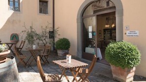 Een terras met houten tafels en stoelen, plantenpotten en een bordje waarop staat dat er een bel is voor bestellingen.