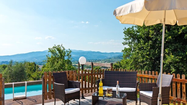 An outdoor patio with wicker furniture, a table with drinks, and a view of a mountain landscape. - Countryside Home in Arezzo with Pool (Tregozzano, Arezzo)