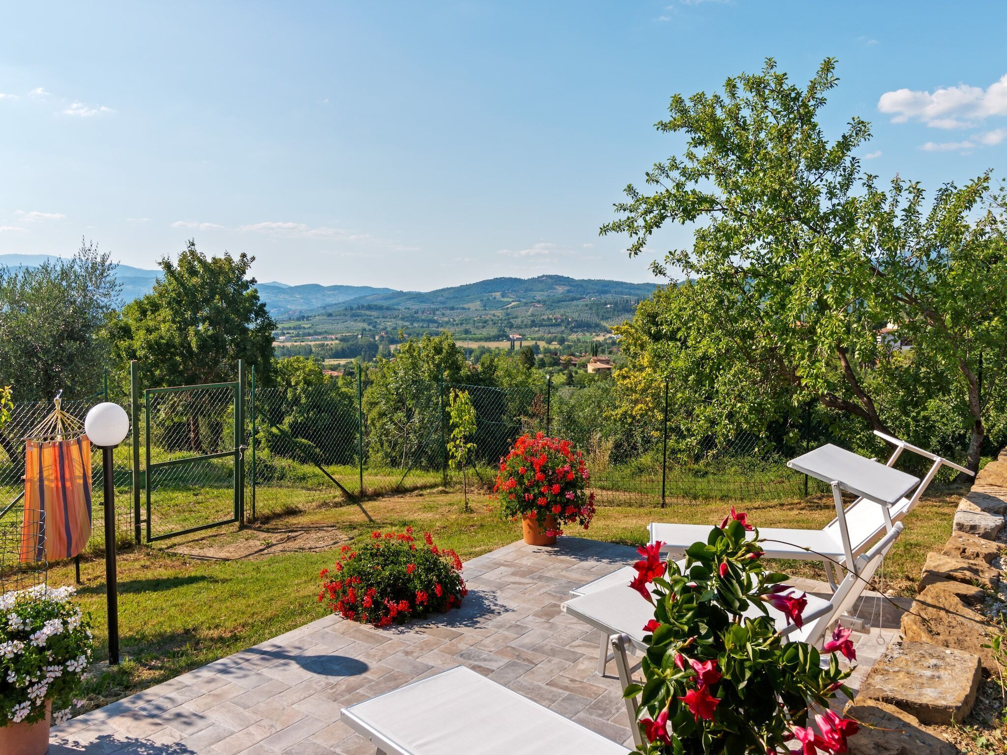 An outdoor patio with white lounge chairs, a stone pathway, and a view of a mountainous landscape.