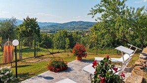 An outdoor patio with white lounge chairs, a stone pathway, and a view of a mountainous landscape. - Countryside Home in Arezzo with Pool (Tregozzano, Arezzo)