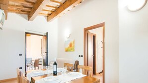 A dining area with a wooden table set for four, a painting on the wall, and a door leading to another room. - Panoramic Countryside Home (Apecchio)