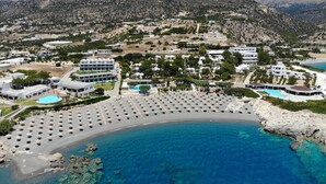 A coastal resort with a large sandy beach, clear blue waters, and mountainous terrain in the background. - Kakkos Bay (Ierapetra)