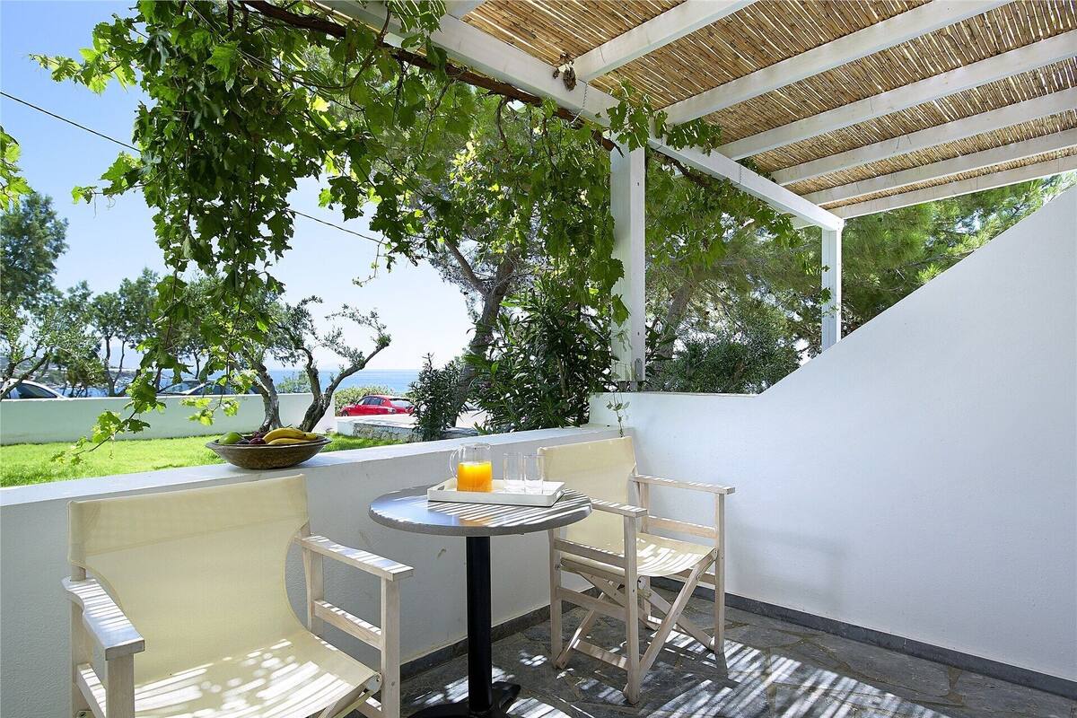 A patio with a table and chairs, a bowl of fruit, and a pitcher of orange juice.