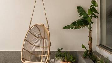 A hanging chair, a potted plant, and a round table in a modern interior space.