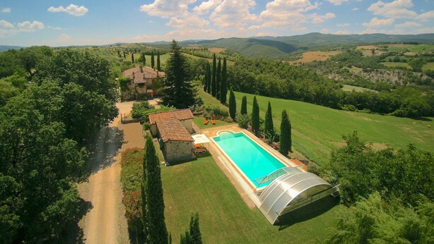 A large swimming pool with a glass enclosure, surrounded by lush greenery and a clear sky. - Elysian Escape - A paradise (San Venanzo)