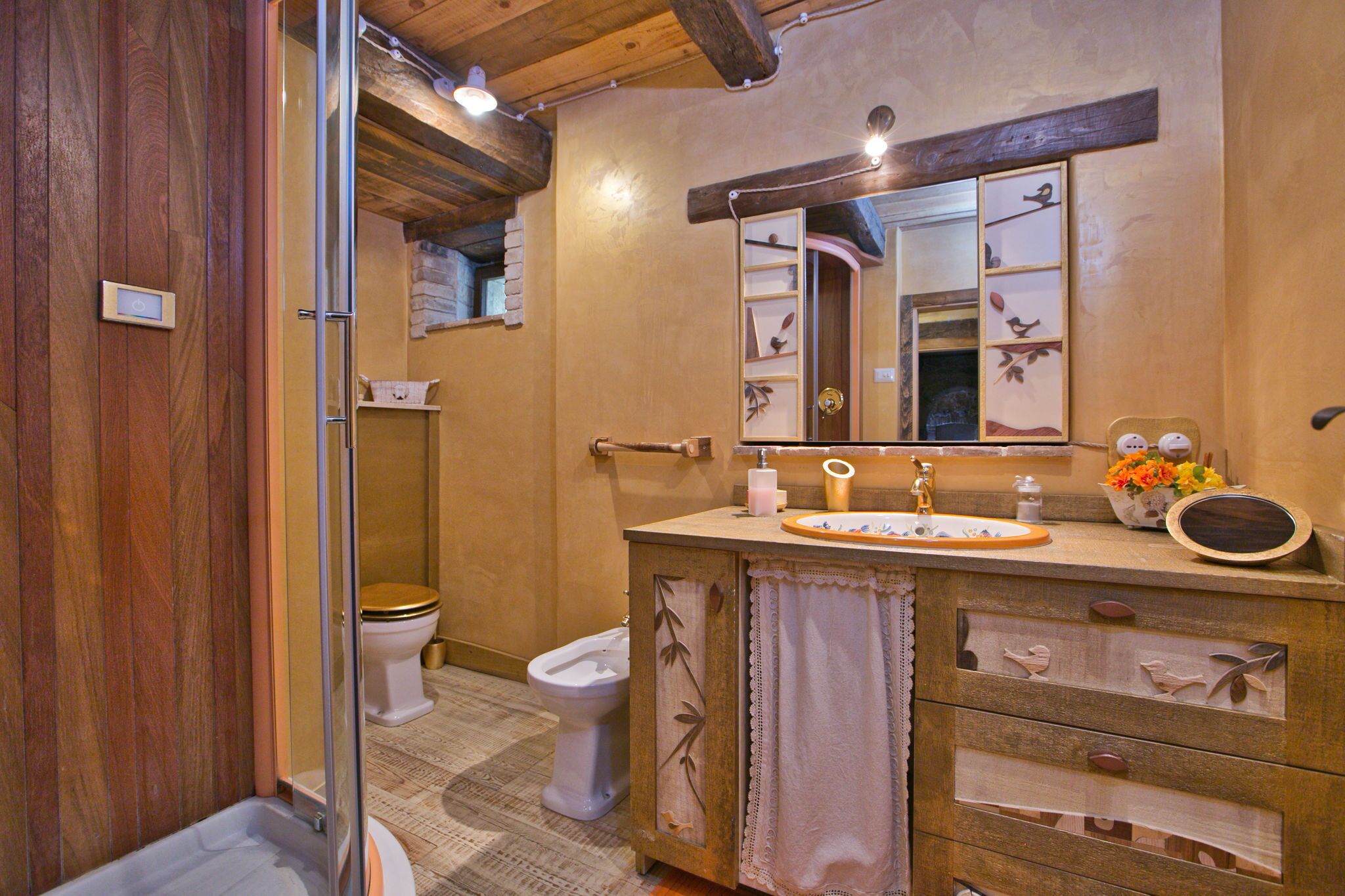 A bathroom with a wooden vanity, a sink, a mirror, and two toilets.