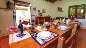 Un comedor con una mesa de madera dispuesta para una comida, un refrigerador y varios utensilios de cocina.