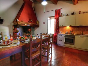 Eine gemütliche Küche mit Holztisch, gedecktem Esstisch, einem roten Schornstein und weißen Schränken.