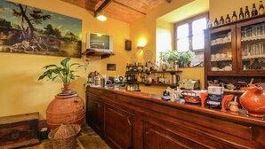 Een bar met houten toonbanken, een aan de muur bevestigde televisie en diverse flessen en glazen op planken.