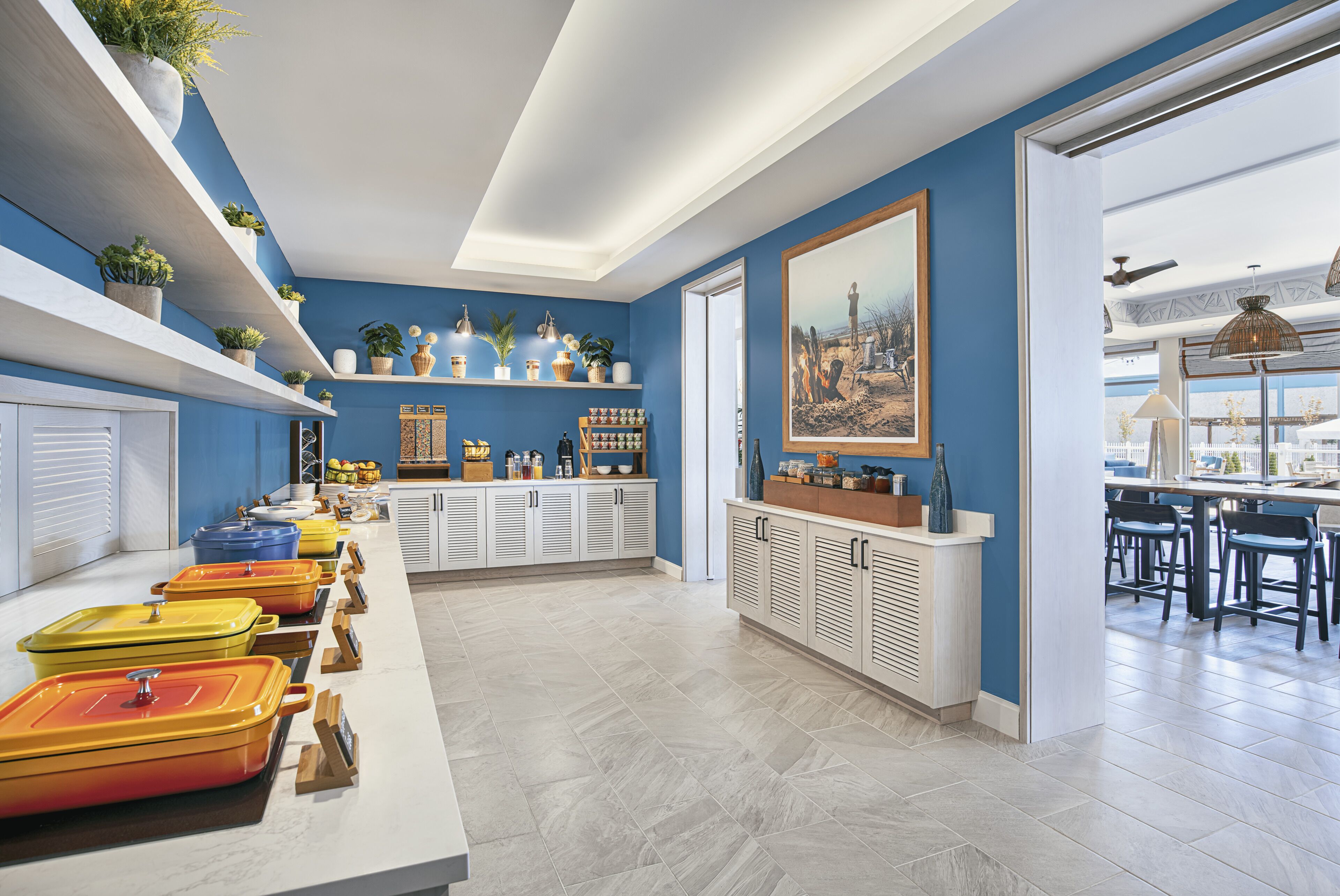 Una cocina moderna con paredes azules, armarios blancos y una variedad de platos de servicio coloridos.