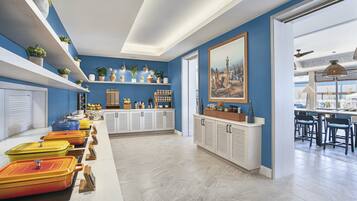 Una cocina moderna con paredes azules, armarios blancos y una variedad de platos de servicio coloridos.