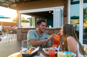 Una pareja cenando al aire libre en un restaurante, con una barra de fondo.