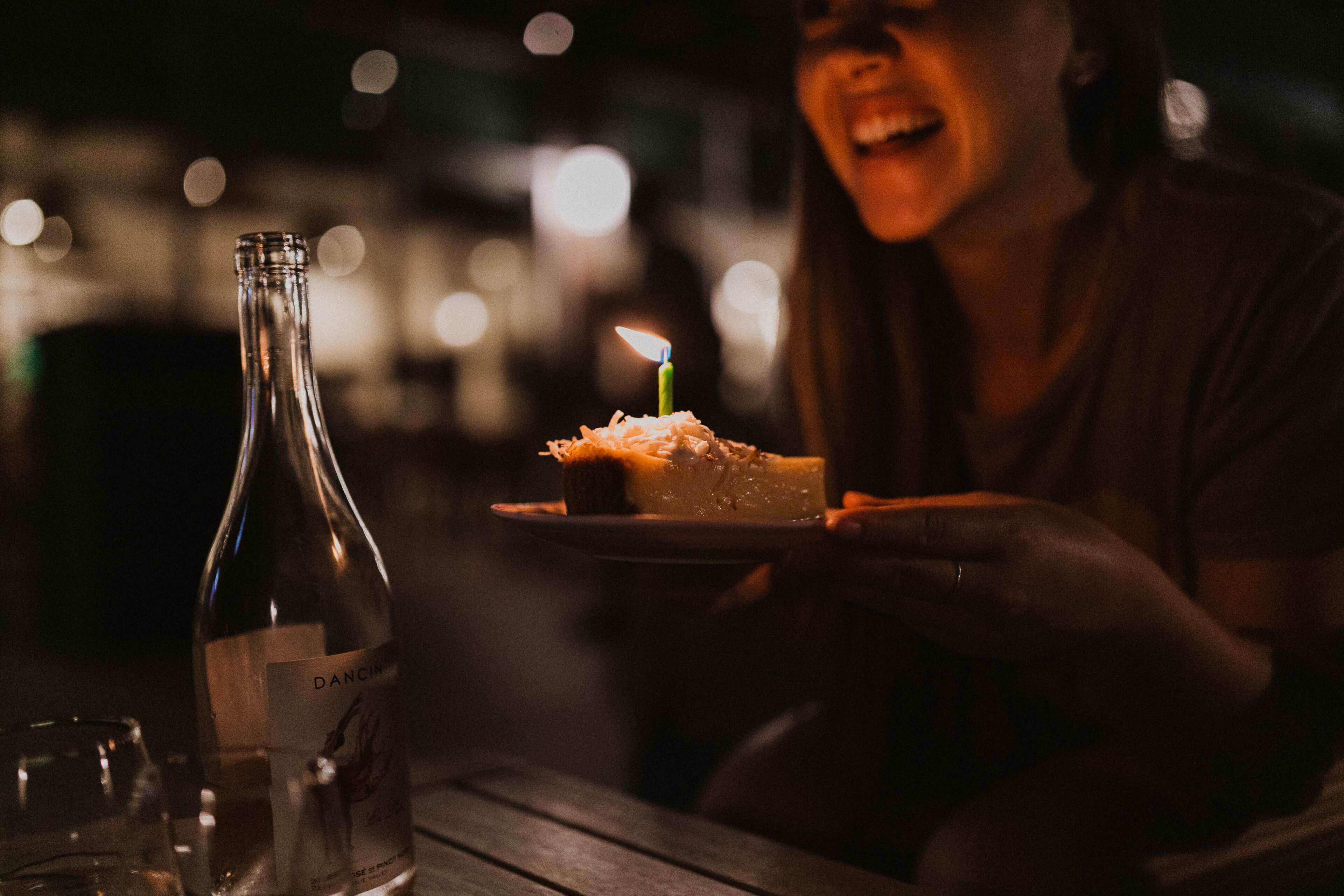 A bottle of wine and a plate with a cake on a table.