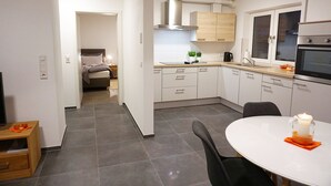 Une cuisine moderne avec des meubles blancs, une cuisinière et un coin repas comprenant une table et des chaises.
