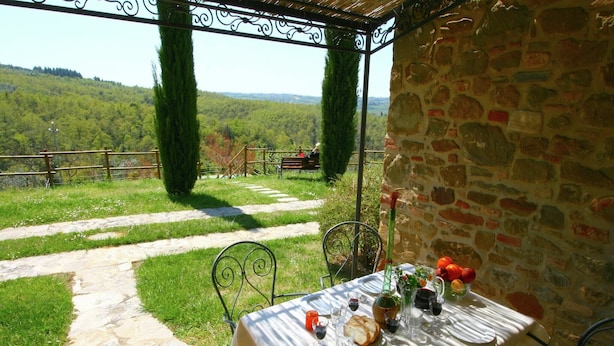 Un espacio de comedor al aire libre con un muro de piedra y vistas al campo.