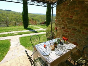 An outdoor dining area with a stone wall and a view of the countryside. - Farmhouse in Città della Pieve with Pool (Città Della Pieve)
