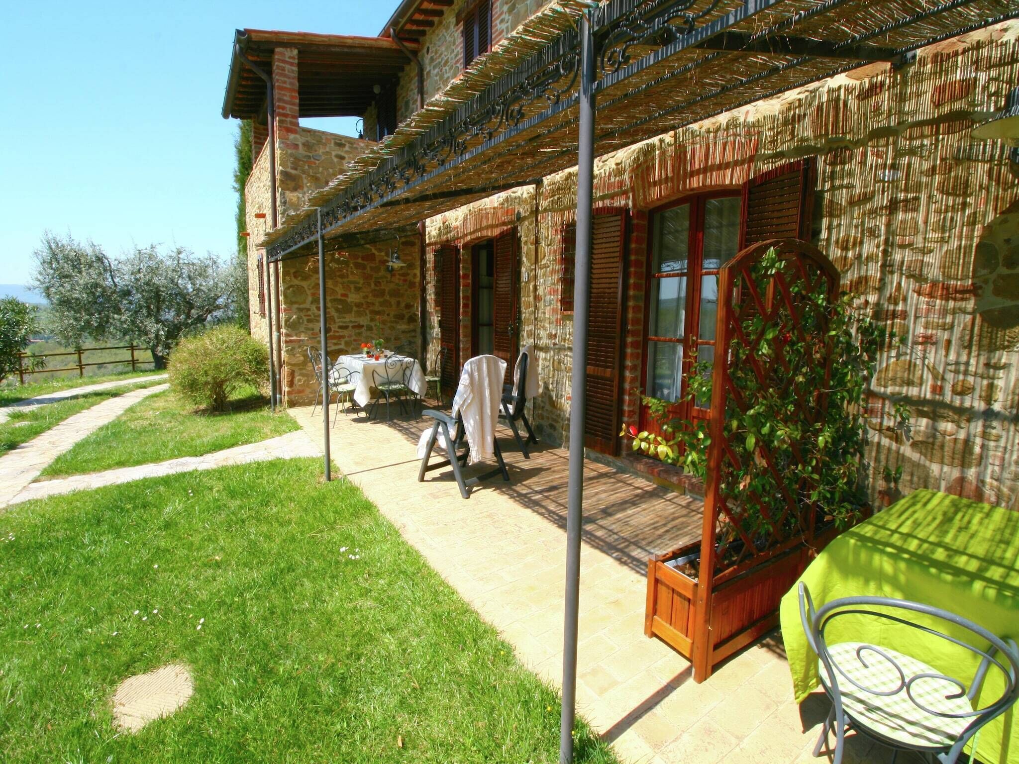 A stone building with a covered patio area, outdoor seating, and a garden.