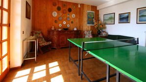 A room with a ping pong table, wooden walls, and a tiled floor.