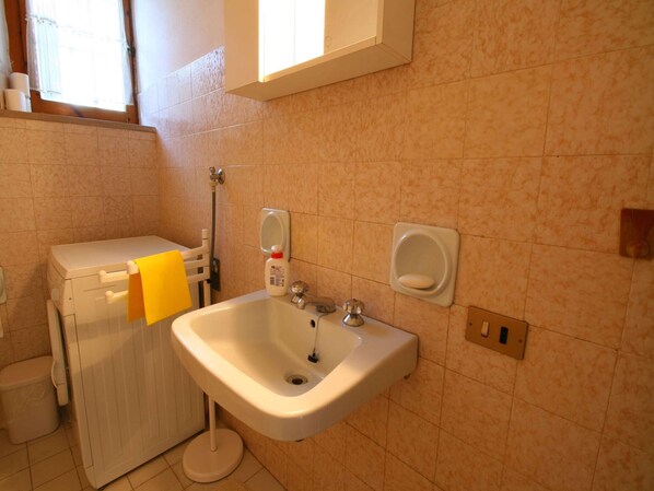 A bathroom with a toilet, sink, and hand soap dispenser.