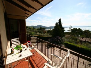 A balcony with a table and chairs, overlooking a scenic landscape with mountains and a body of water.