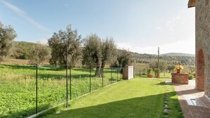 Een verzorgde tuin met een stenen muur, een pad en uitzicht op het landschap.