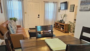 A dining area with a wooden table, dark chairs, a ceiling fan, and a television on the wall. -   5min drive to Universal studio (Orlando)