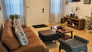 A living room with a brown sofa, a blue armchair, a coffee table, and a ceiling fan. -   5min drive to Universal studio (Orlando)