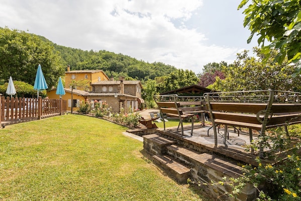 Une cour avec un banc en bois, un escalier en pierre et un bâtiment jaune.