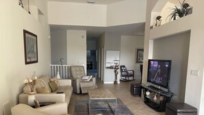 Ein modernes Wohnzimmer mit einem beigen Sofa, einem Liegesessel, einem Fernseher und einem Couchtisch.
