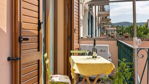 Ein Balkon mit Tisch und Stühlen, einer Champagnerflasche und Blick auf die Umgebung.