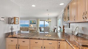 Cocina con encimeras de granito, armarios de madera y vista al área de estar.