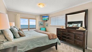 Un dormitorio con cama, cómoda y televisor en la pared.