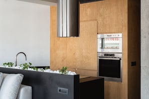 A modern kitchen with a built-in oven, stainless steel range hood, and a wooden backsplash.