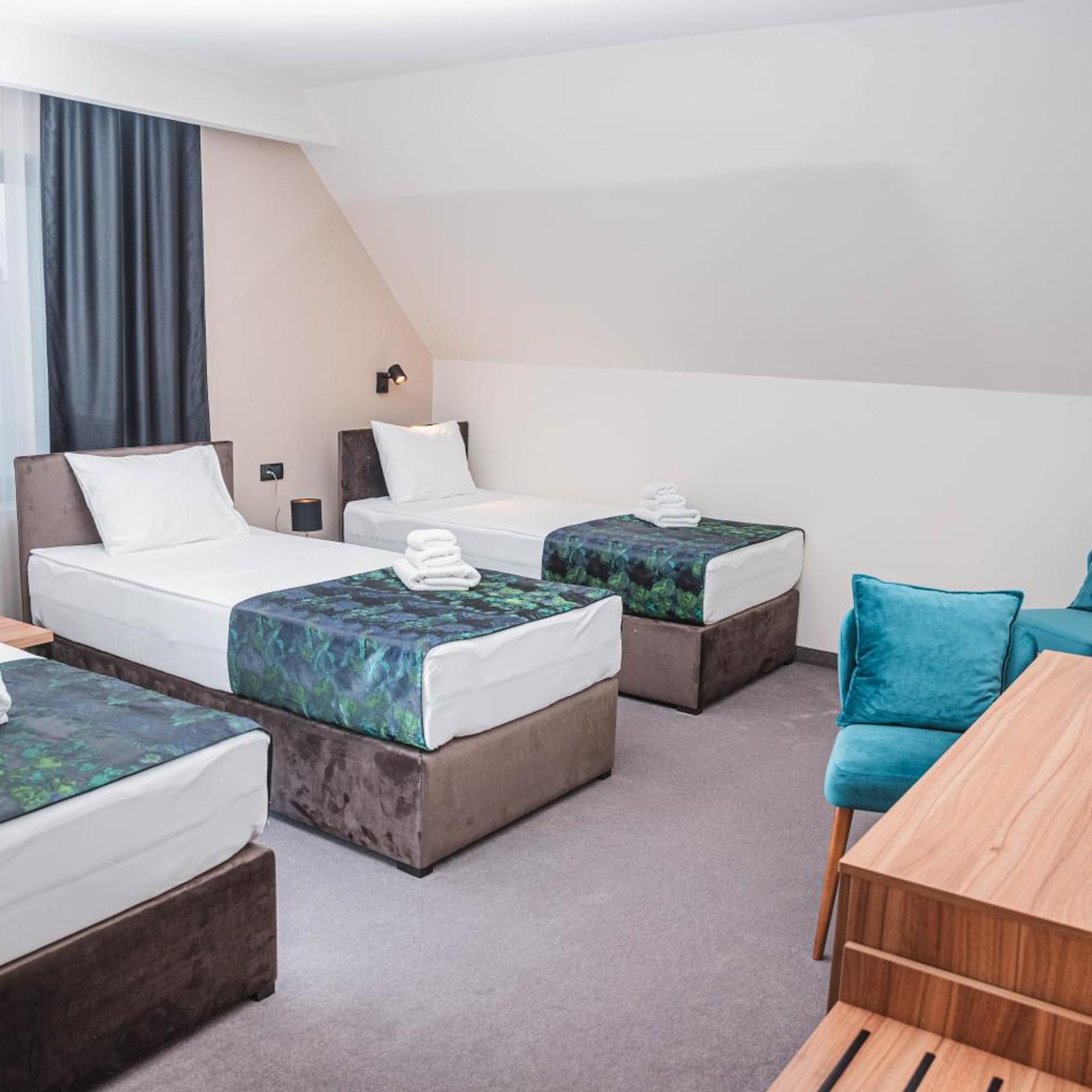 A hotel room with two beds, a small table, and a couch.