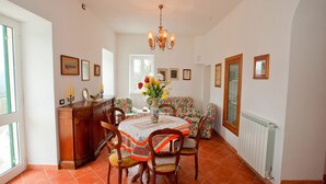 A dining area with a round table, chairs, a chandelier, and a window with a view.