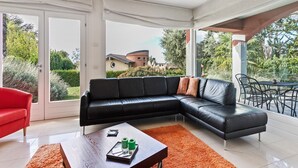 Ein modernes Wohnzimmer mit einer schwarzen Ledersofa, einem Holztisch und einem roten Sessel.