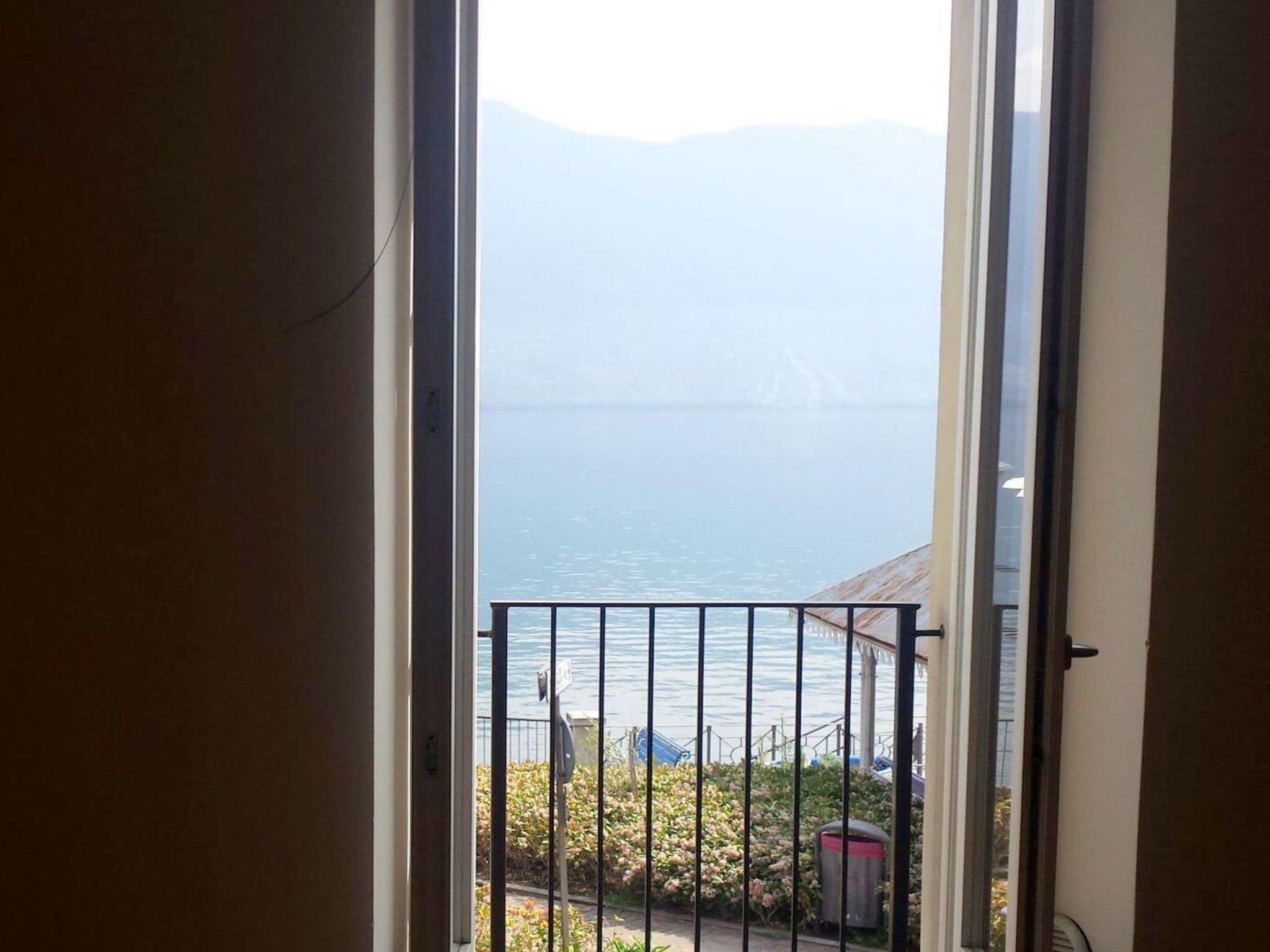 Vista da un balcone con ringhiera in metallo, su un corpo d'acqua e montagne lontane.
