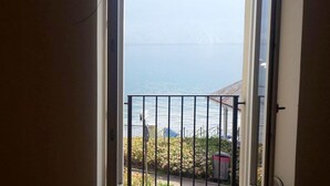 Vista desde un balcón con barandilla de metal, sobre un cuerpo de agua y montañas distantes.
