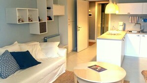 Una sala moderna con un sofá, una mesa de centro y un área de cocina con una mesa de comedor.
